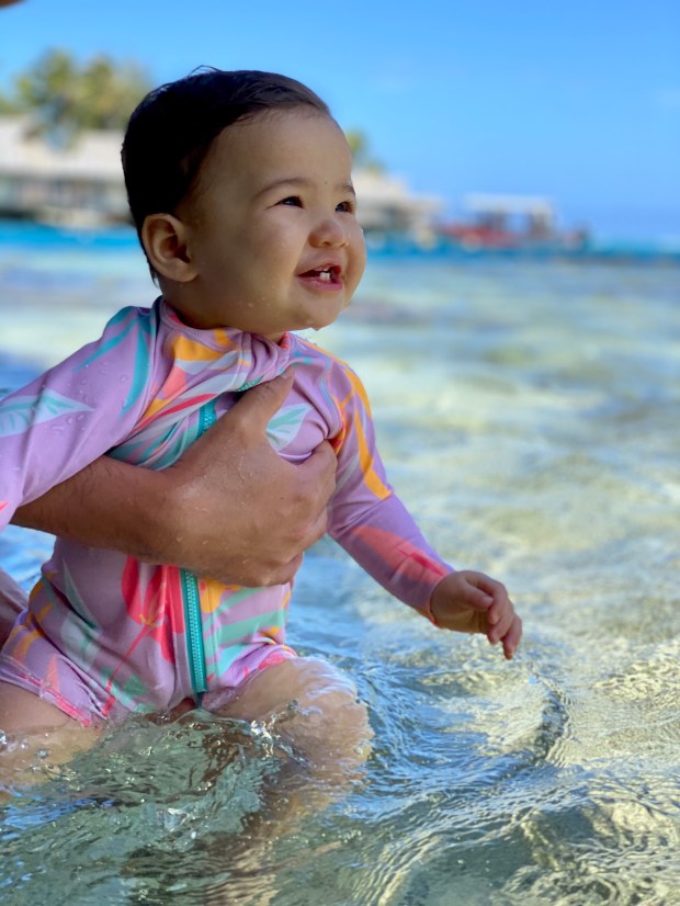 A smiling, happy baby on vacation and swimming in the ocean