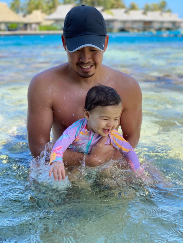 Dad and baby smiling and splashing in the ocean 