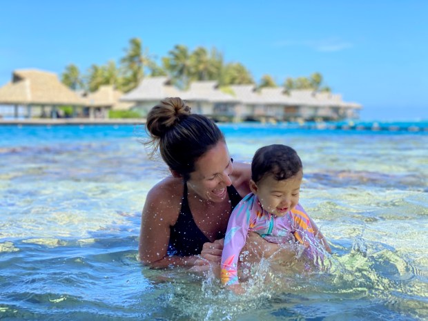 Mom and baby splashing in the turquoise water in Tahiti