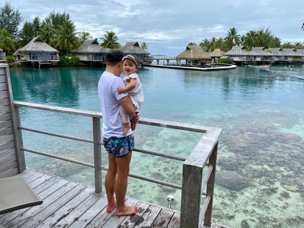 Dad and baby looking at clear ocean water in Moorea, French Polynesia
